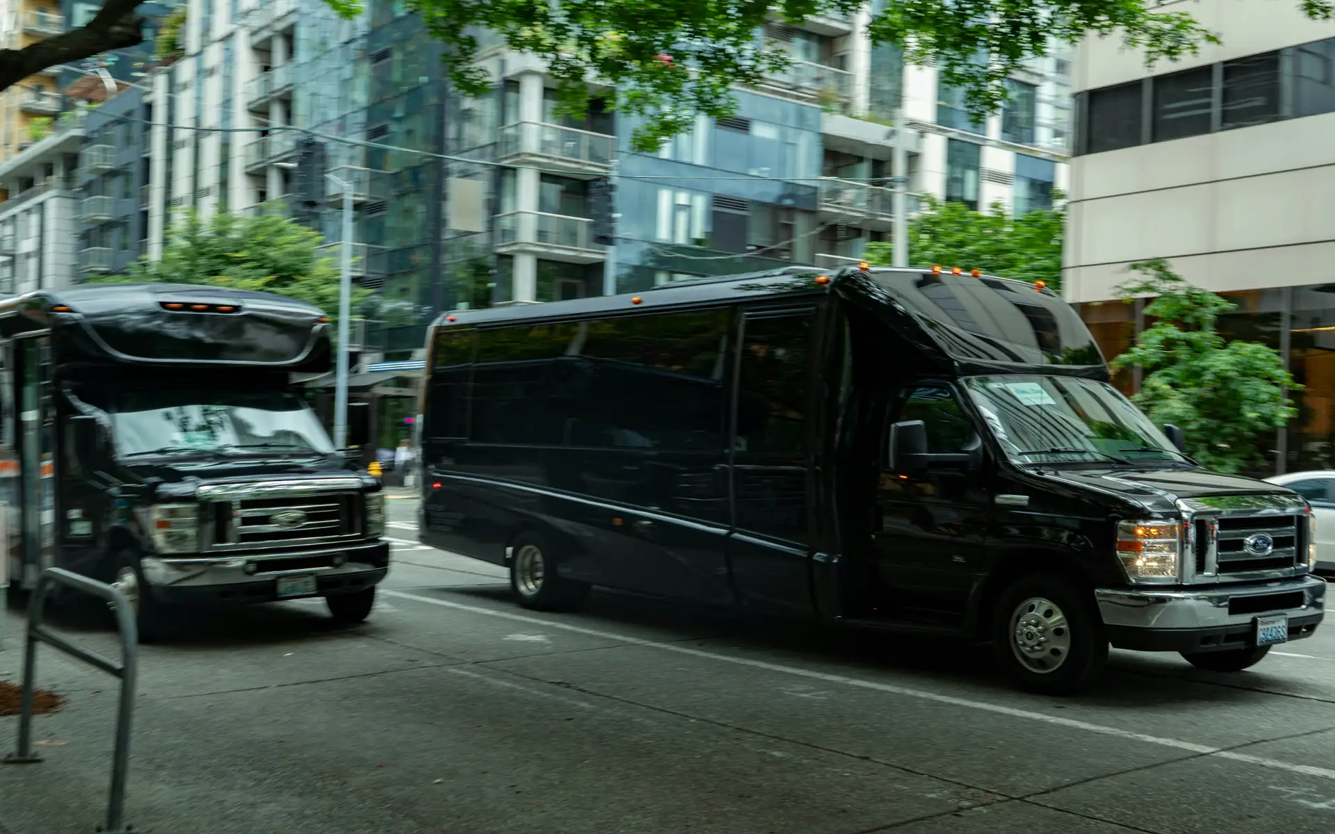 Two black party buses on a city street