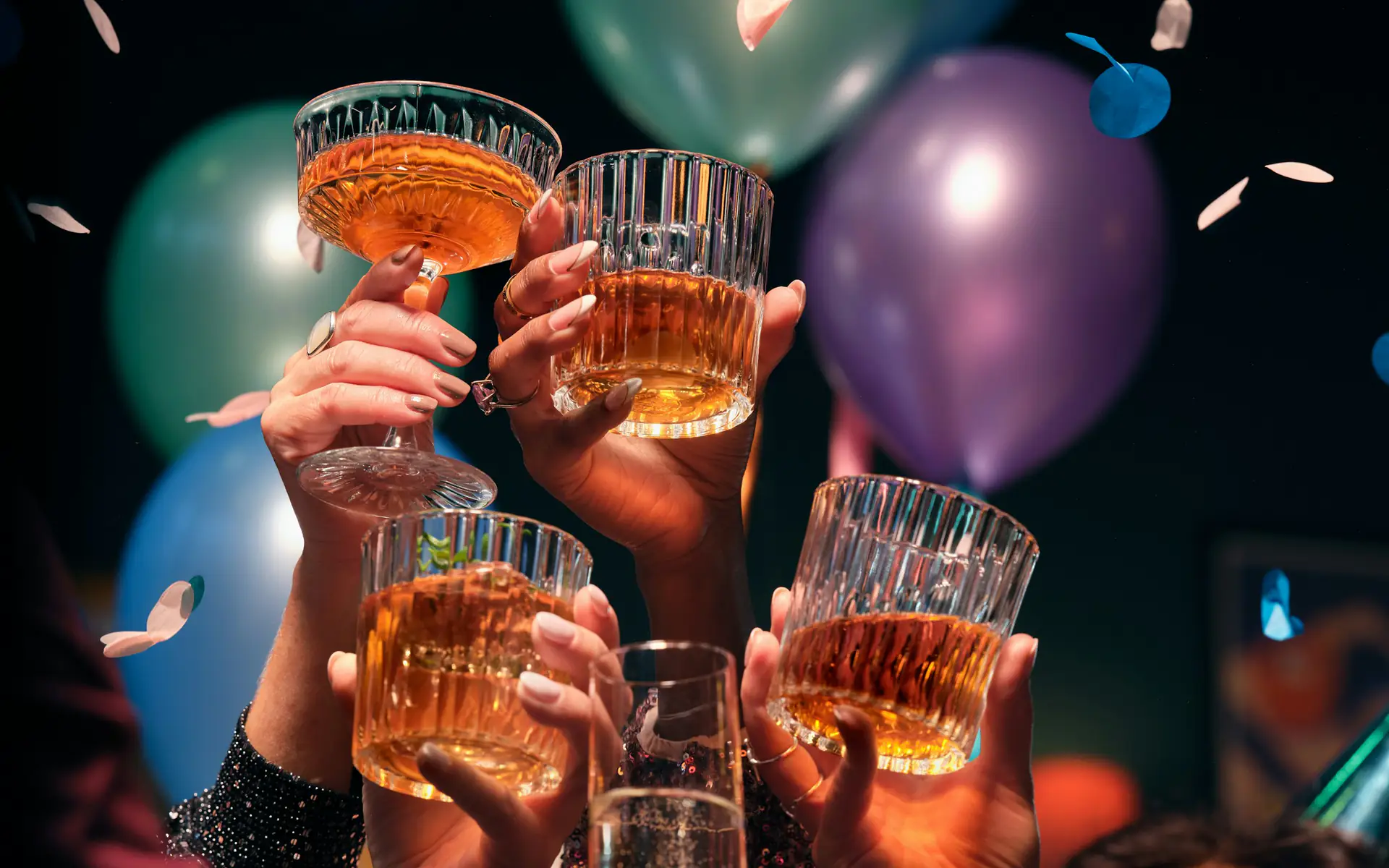 Friends raising glasses in a toast at a party with balloons