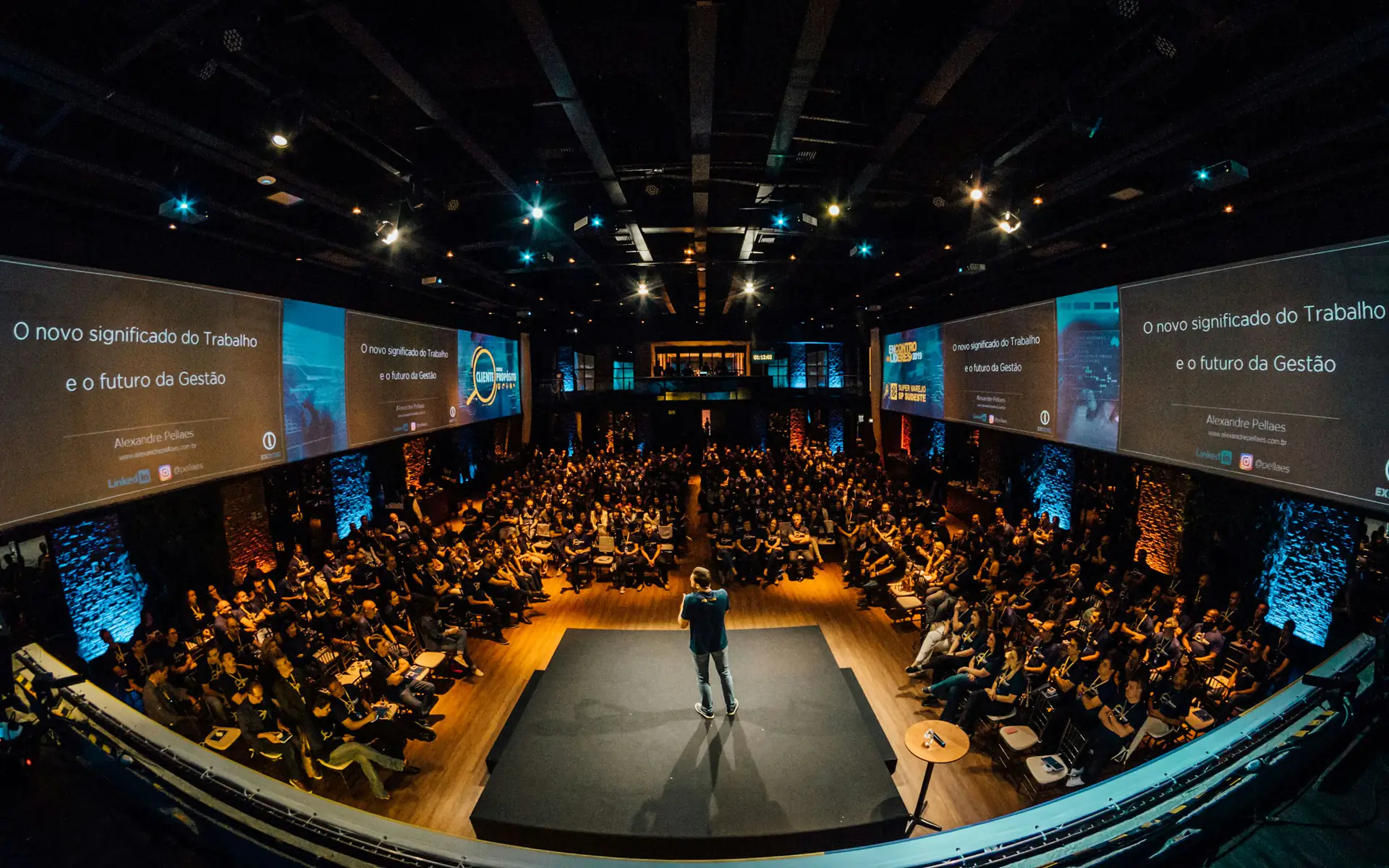 Speaker on stage presenting to a large conference audience