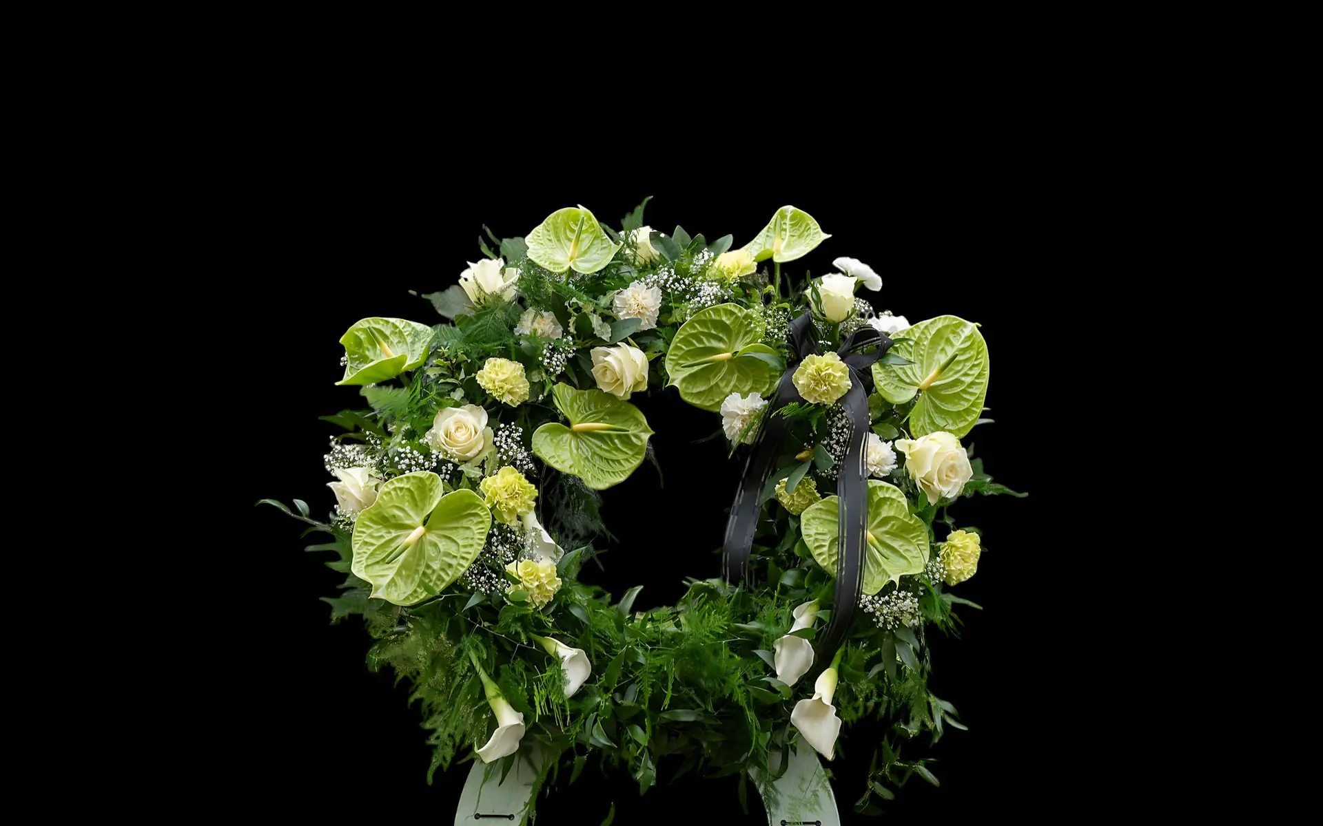 White and green floral wreath on a dark background