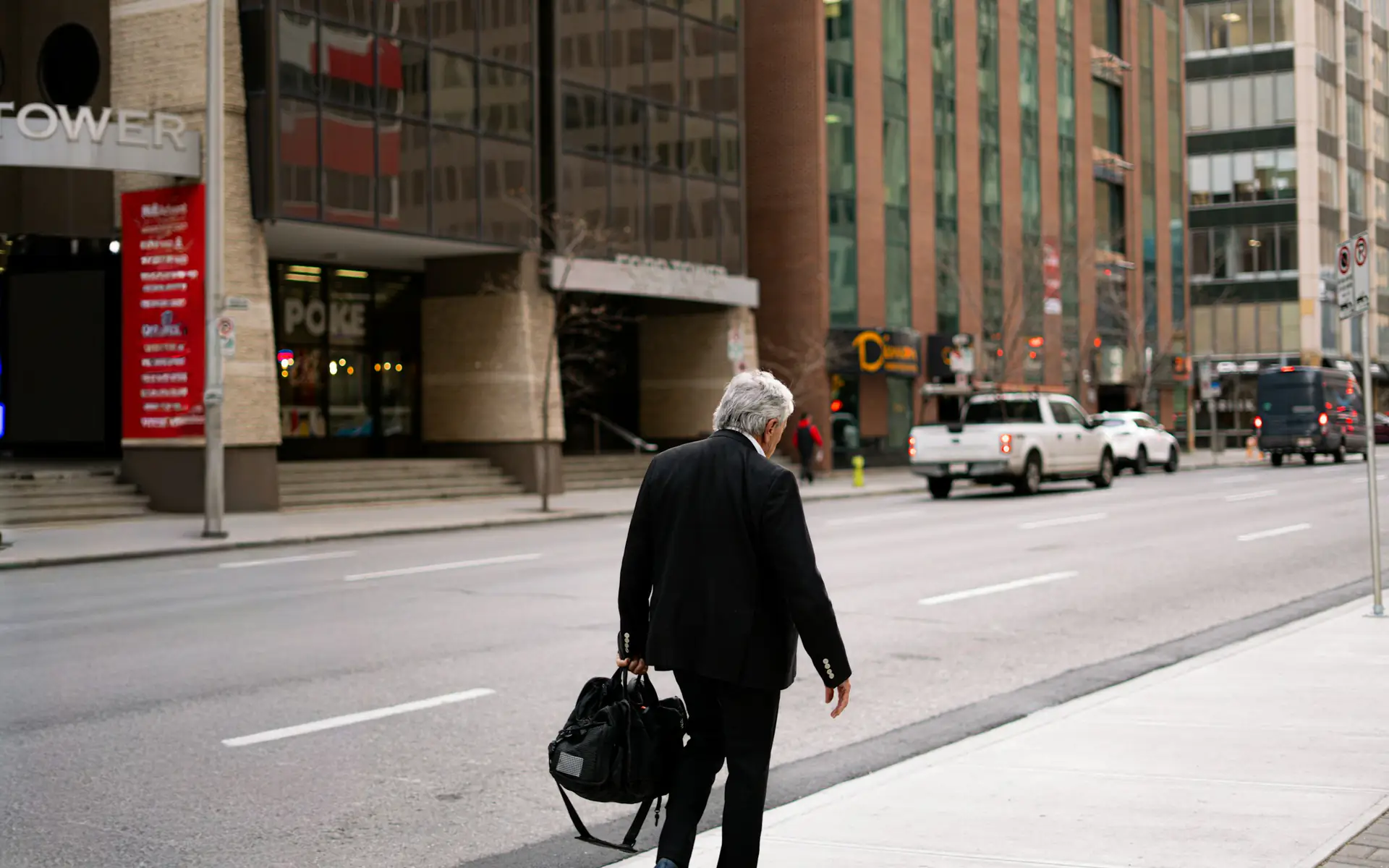 Businessman in a suit carrying a bag along a downtown street