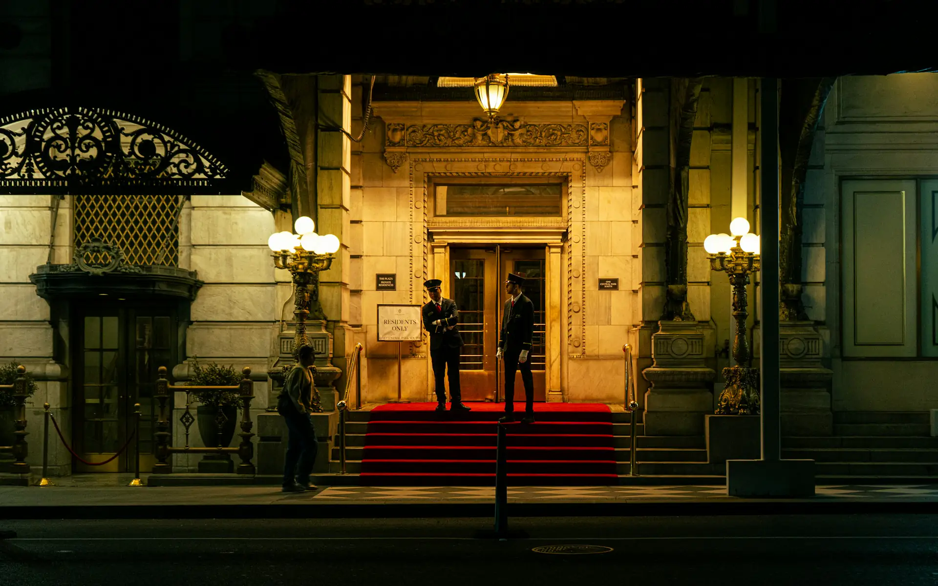 Hotel entrance with a red carpet and doormen at night